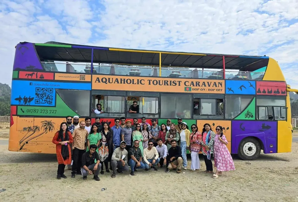 The team posing in front of a colourful tourist caravan